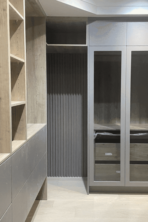 A fitted dressing room with fluted panelling and glass-front wardrobes, built by Alliance Cabinets